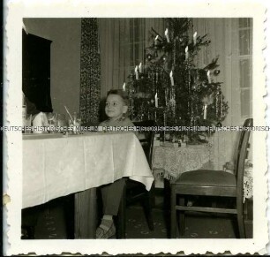 Kleiner Junge am Tisch vor Weihnachtsbaum