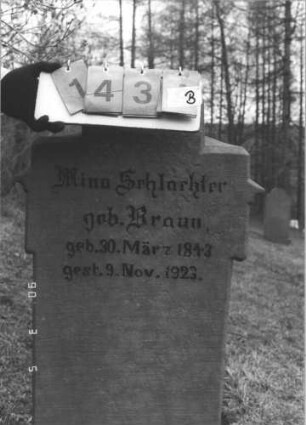 Grabstein 143 (Index: 99608827) Material: Sandstein Zustand: beschädigt mit kleinem Textverlust Maße HxBxT: 131x58x22 cm Beschreibung: Stele, getreppter Rustikasockel, getreppter giebelaritger Abschluß, Schriftfeld eingetieft mit Spitzbogenabschluß: Grabstein 143B
