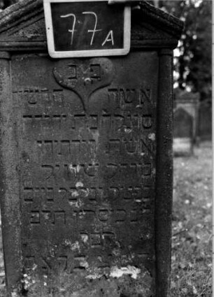 Grabstein 77 (Index: 100111160) Material: Sandstein Zustand: leicht verwittert Maße HxBxT: 122x62x13 cm Beschreibung: ädikulaartige Stele mit Halbsäulen, Sockel, Giebel mit Verdachung Symbolik: Herz, Blüte: Grabstein 77A