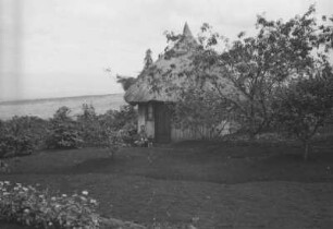 Hütte von Martin George : Hütte in einem Garten. Davor sitzt ein Mann