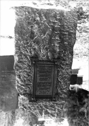 Grabstein 32 (Index: 100092754) Material: Obelisk: Granit; Platte: Metall? Maße HxBxT: 154x70x40 cm Beschreibung: grobbehauener Obelisk mit aufgesetzter Schriftplatte: Grabstein 32 (2)