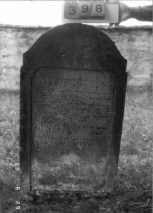 Grabstein 398 (Index: 100107888) Material: heller Sandstein Zustand: verwittert, stark versalzen Maße HxBxT: 125x67x18 cm Beschreibung: Stele mit geschwungen eingezogenem Rundbogenabschluß, Schriftfeld rechteckig eingezogen: Grabstein 398