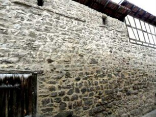 Kirchhofmauer im Südosten über Ortsseite-erhaltener Wehrgang mit Steinbrüstung (Teil über Schießscharte bis Dachkante abgetragen) und Schießscharten-aus innen angebauten Gaden zu bedienen