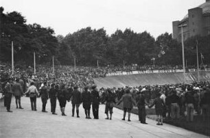 Blick in die Radrennbahn in Reick während der Wahlveranstaltung der KPD, an der Bande die Losung:"Kommunismus ist der einzige Ausweg!", im Hintergrund das Gasometer Reick