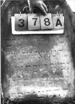 Grabstein 378 (Index: 100115722) Material: Sandstein Zustand: verwittert Maße HxBxT: 85x55x12 cm Beschreibung: Stele mit eingezogenem Rundbogenabschluß, eingetieftes Schriftfeld Symbolik: Levitenkanne: Grabstein 378A