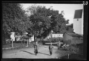 General von Staudt und Oberleutnant von Kress mit Pickelhaube und Mänteln auf einer Ortsstraße mit der Ortskirche im Hintergrund