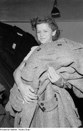 Portrait einer jungen Frau beim Transportieren von Trenchcoats im VEB Bekleidungswerk Leipzig