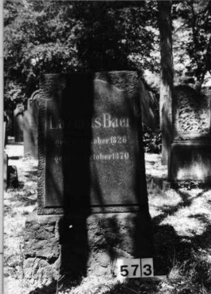 Grabstein 573 (Index: 99630075) Material: Granit mit geschliffener Platte Zustand: gut Maße HxBxT: 105x63x41 cm Beschreibung: Stele auf Sockel, Schriftplatte mit Rundbogenabschluß: Grabstein 573