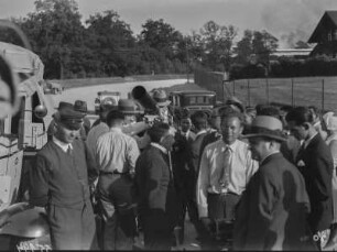 Auf der AVUS : Menschen auf der AVUS, versammelt neben einem LKW. Im Hintergrund einige PKW. Es scheint, als würde hier der Expeditionszug vorgestellt.
