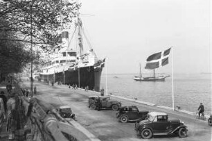 Reisefotos Dänemark. Kopenhagen. Hafen. Automobile am Kai mit Danebrog. Dahinter das Passagierschiff "Monte Rosa"