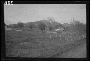 Domnetal (=Tal des Râul Doamnei, Fluss in Rumänien): Haus auf einer Anhöhe, im Hintergrund drei Berge (Distanzaufnahme)