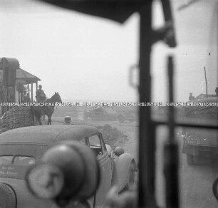 Rumänischer Soldat auf einem Pferd und LKW der Wehrmacht auf einer Landstraße, aus einem LKW heraus fotografiert