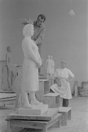 Beim Modellieren einer stehenden Frau mit verschränkten Händen. Gips (1960/1962) (Studentenarbeit der Bildhauerklasse von Walter Arnold)