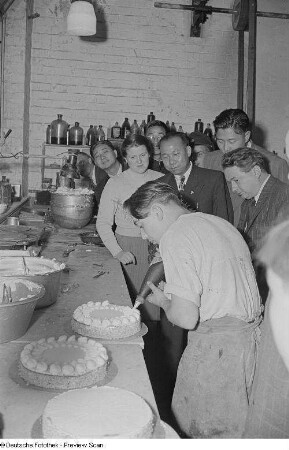 Chinesische Delegierte sehen beim Verzieren einer Torte zu