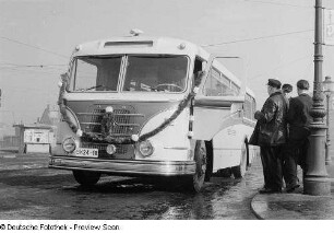Personen betrachten einen mit Girlanden geschmückten Omnibus H6B