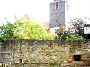 Ansicht von Südwesten mit Kirche über Kirchhofmauer von Feldseite in Übersicht mit Schießscharte (runde Kreis- oder Büchsenscharte mit Öffnungswinkel nach außen)-Wehrgang abgetragen