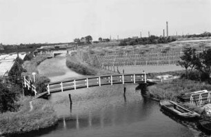Glashauslandschaft-Westerland : Blick über eine Landschaft mit einem kleinen Kanal, einer Brücke und Gewächshäusern