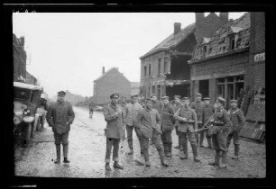 Nicht identifizierbare Ortschaft bei La Bassée (Dep. Nord, Frankreich), Haisnes (Dep. Pas-de-Calais, Frankreich), Orchies (Dep. Nord, Frankreich), Willerval (Dep. Pas-de-Calais, Frankreich), Acheville (Dep. Pas-de-Calais) oder Roclincourt (Dep. Pas-de-Calais, Frankreich): Soldatengruppe auf einer morastigen Ortsstraße, im Hintergrund Gebäuderuinen