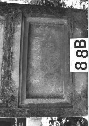 Grabstein 88 (Index: 100114221) Material: Sandstein Zustand: stark verwittert mit großem Textverlust, gebrochen und repariert Maße HxBxT: 187x59x28 cm Beschreibung: Stele, Sockel, Rundbogenabschluß mit Mittelakroter, deutsches eingetieftes Schriftfeld rechteckig Symbolik: Palmette als Mittelakroter: Grabstein 88B