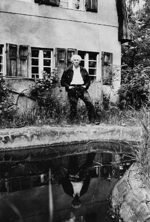 Der Schriftsteller Erich Arendt im Garten in Wilhelmshorst, an einem Gartenteich stehend