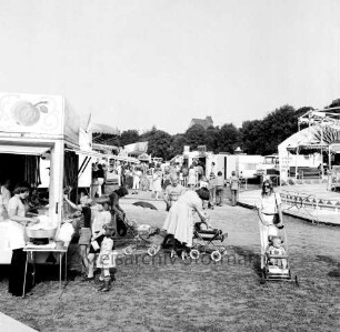 Volksfestplatz: an Sehmsdorfer Straße: Karussell, Jahrmarktbuden: drei Mütter mit Kinderwagen, links Kinder an Stand mit Zuckerwatte, Besucher, Kinder: im Hintergrund Bäume, Weizenmühle ("Gloria-Mühle") der Johannes Ströh Mühlenwerke am Pferdemarkt