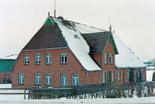 Voßkaten 6: giebelständiges Bauernhaus: Straßenfront Wohntrakt, oben Eulenloch, Giebelpfahl: Traufseite, vorne Wohntrakt mit Eingangstür, darüber Zwerchgiebel mit Giebelzier, hinten Wirtschaftstrakt mit Fachwerk, Kletterpflanzen: hinten links Wirtschaftsgebäude: in Vordergrund Hecke, Zaun