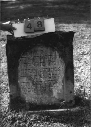 Grabstein 48 (Index: 100113841) Material: Sandstein Zustand: oberer Teil abgebrochen Maße HxBxT: 75x58x15 cm Beschreibung: Stele mit Spitzgiebel und Bogenfries, vertiefter Textteil in Form einer Stele mit Rundbogen: Grabstein 48