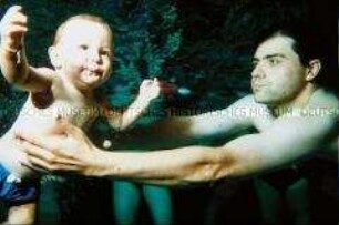 Mann mit unter Wasser schwimmenden Baby (Altersgruppe 14-17)