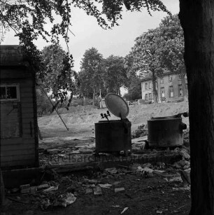 Bürgerpark: Volksküche: Abriss: vorn zwei Kochkessel und Ecke einer Baracke: dahinter Ausschachtung für Bau der Stormarnhalle und Bretterstapel: hinten rechts ehemaliges Unfallkrankenhaus und Schuppen