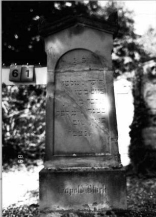 Grabstein 61 (Index: 100086513) Material: Sandstein Zustand: gebrochenen und repariert mit Textverlust Maße HxBxT: 150x54x16 cm Beschreibung: Stele, getreppter Sockel, giebelartiger Abschluß mit Verdachung und Eckakroteren, eingetieftes Schriftfeld mit Rundbogen: Grabstein 61
