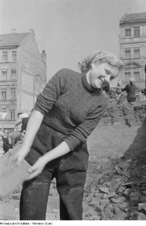 Eine junge Frau auf der Baustelle Chausseehaus wirft einen Ziegelstein
