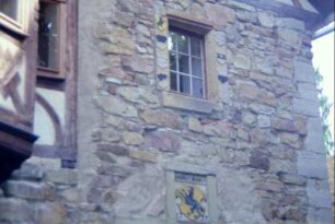 Farbig gestaltetes Wappen an der Würzburger Kemenate; darüber Fenster mit Wappenreliefs auf den Gewändesteinen
