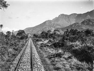 Eisenbahntrasse : Blick auf eine Eisenbahntrasse durch die Savanne. Im Hintergrund ein Gebirgsmassiv