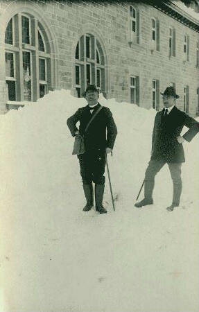 Schinzinger mit Begleitperson in Zivil im Schnee vor Haus [Krankenhaus, Erholungsheim?]