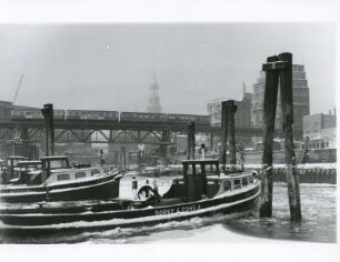 Hamburg. Winter. Verschneite Fähren liegen vertäut im vereisten Wasser am Baumwall. Im Hintergrund die Silhouette der Freien- und Hansestadt