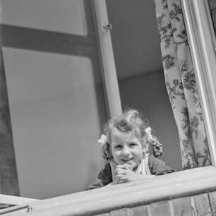 Mädchen mit Zöpfen schaut aus dem Fenster