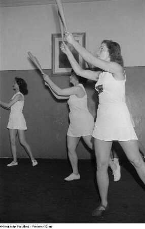 Sportlerinnen während einer Gymnastikübung mit Keulen