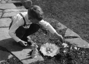 Kinderbilder. Kleiner Junge mit Osternest in einem Garten