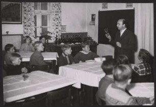Bei einem Kurs über gute Tischsitten zeigt der Lehrer den Schülern in Weinglas