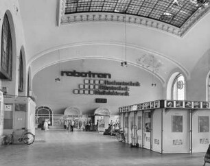 Bahnhof Dresden-Neustadt. Empfangsgebäude, Schalterhalle. Blick zur Nordostseite mit Werbe-Leuchtschrift für Rechentechnik, Bürotechnik und Meßelektronik von robotron : Dresden-Neustadt, Schlesischer Platz 1. Bahnhof Dresden-Neustadt. Empfangsgebäude, Schalterhalle. Blick zur Nordostseite mit Werbe-Leuchtschrift für Rechentechnik, Bürotechnik und Meßelektronik von robotron