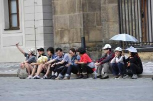 Chinesische Touristen : Ermüdete chinesische Touristen sitzen vor dem Eingang zur Burg auf der Erde. Aufgenommen in Prag am 31. Juli 2009