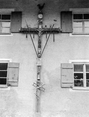 Kruzifix mit Marterwerkzeugen an einer Hausfassade wohl am Weißensee im Allgäu
