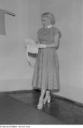 Eine Frau posiert mit Sommerkleid und Handtasche bei der "Internationalen Messemodenschau", Herbstmesse 1953