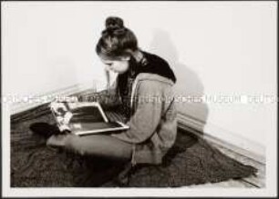 Sitzendes Mädchen schaut sich Buch an (Prämiertes Foto G)