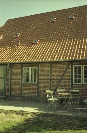 Benstaben 11: traufständige Fachwerkkate mit Ziegeldach: rückwärtige Traufseite, Teilansicht: Tür, Fenster: auf Terrasse Sitzgruppe