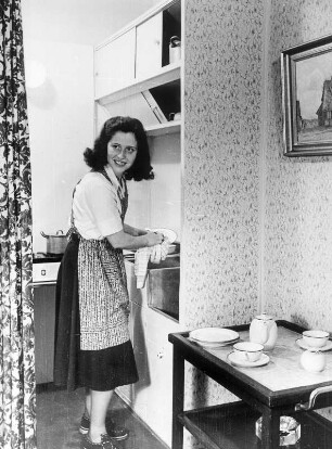 1949. Die ersten Neubauwohnungen sind nach dem Krieg entstanden. Eine Frau hantiert in ihrer Kleinstküche.