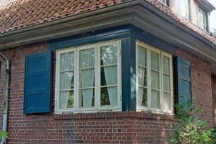 Sieker Landstraße 161: Wohnhaus aus Backstein, mit Zeltdach: Teilansicht: zwei Sprossenfenster über Hausecke, mit Fensterläden