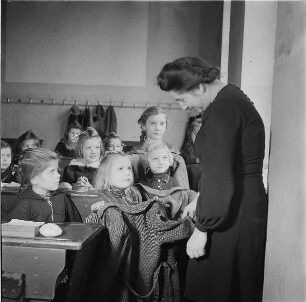 Berlin. Klassenzimmer einer Schule. Lehrerin und Schülerinnen begutachten einen Wintermantel