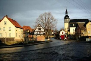 Dorfmitte mit anliegenden Gebäuden, hinten Kirche