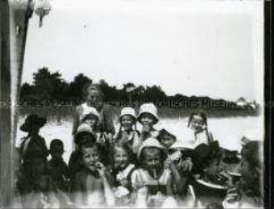 Kindergruppe mit Erzieherin beim Picknick am Strand